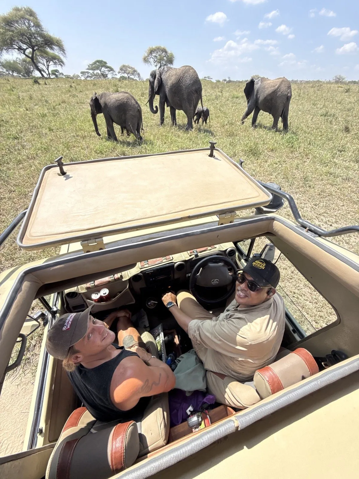 Jackson and Pete on safari with a herd of elephants ahead of the vehicle, Tanzania