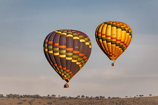 Two hot air balloons over the Mara plains at dawn