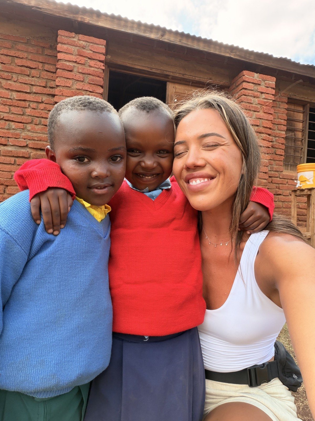 A Kingse Safaris guest with two pupils outside the community school in Karatu, Tanzania