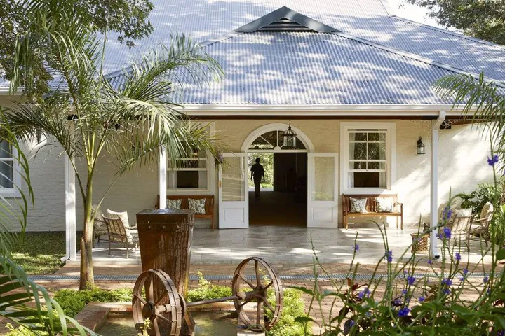 The colonial-style main building among tropical gardens at Pioneers Victoria Falls