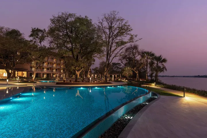 The pool lit at dusk beside the Zambezi at Radisson Blu Mosi-oa-Tunya