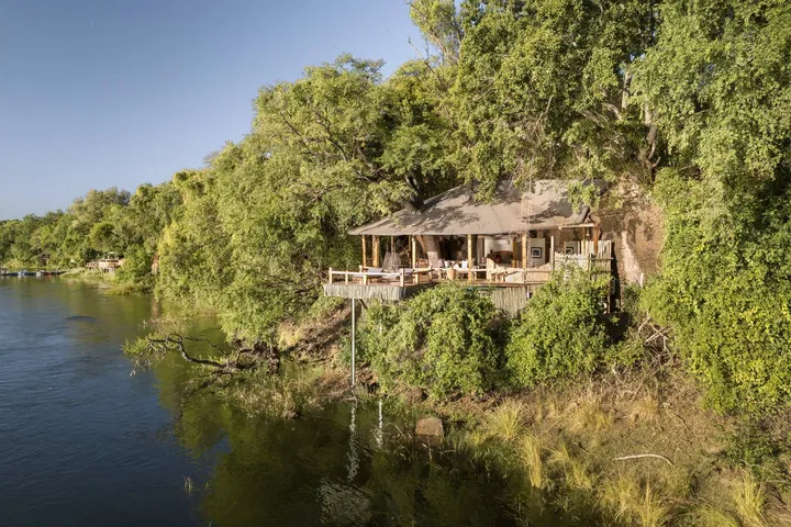 A thatched cottage in the trees above the river at Tongabezi