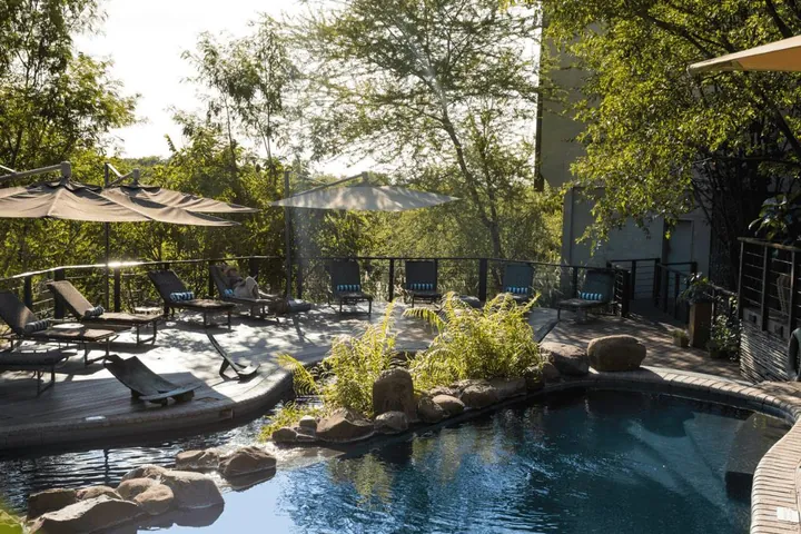 The pool deck among trees at Victoria Falls Safari Club