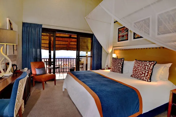 A bedroom with a balcony onto the bush at Victoria Falls Safari Lodge