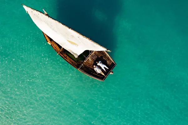 A dhow on clear turquoise water, seen from above