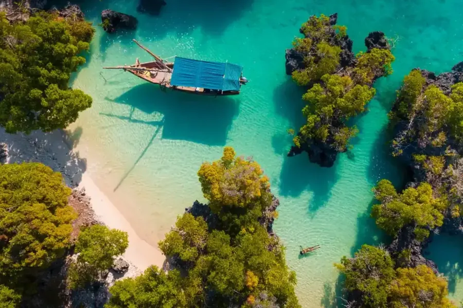 Aerial view of a dhow in a turquoise lagoon among small green islands