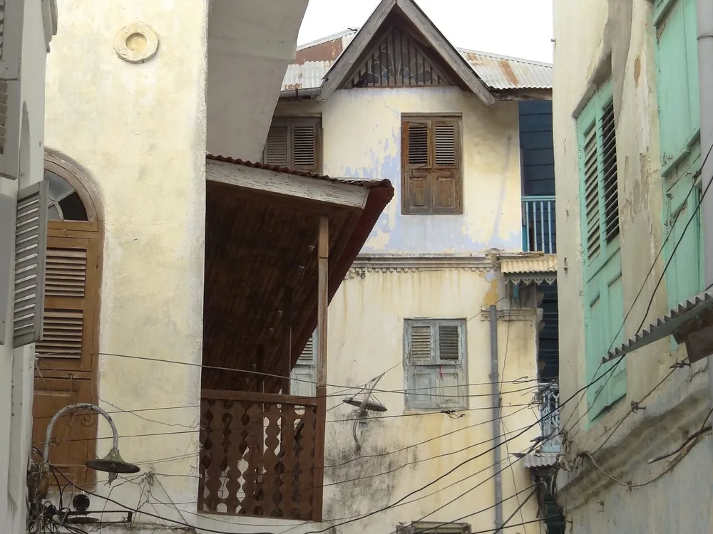 A narrow lane of old coral-stone buildings with carved balconies in Stone Town
